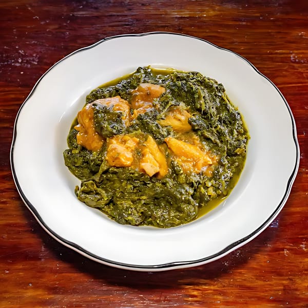 Indian Palak Chicken, a vibrant green spinach curry with tender chicken pieces, served on a white plate.