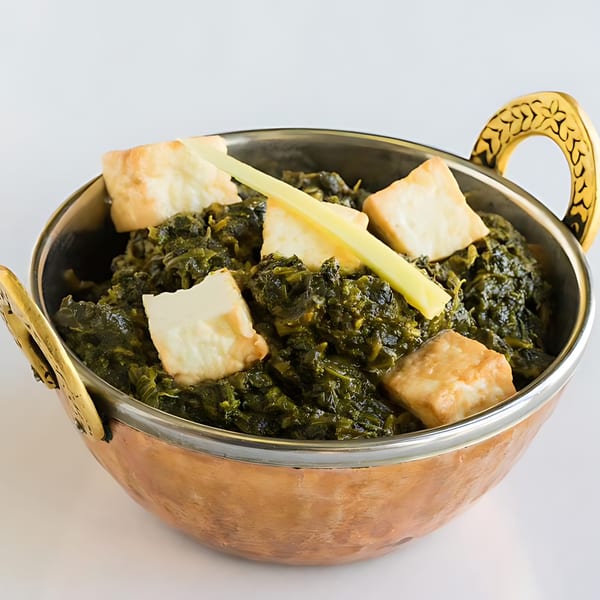 Palak Paneer, a vibrant green Indian spinach and cheese curry, in a copper serving bowl.